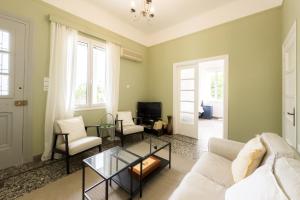 ein Wohnzimmer mit Sofa, Sesseln und Fernseher in der Unterkunft Bright & Cozy House near Beach in Athen