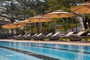 Una piscina con tumbonas y sombrillas junto a una piscina. en Golden Tulip Kin-Oasis Kinshasa, en Kinshasa
