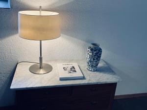 a table with a lamp and a book and a vase at Sust Lodge in Hospental