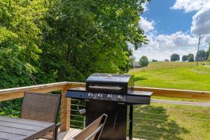 a grill on a deck next to a chair at Riverfront Fishing, Firepit, Only 4 Miles to the Speedway in Bluff City