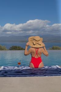 Une femme dans un chapeau assise sur la plage dans l'établissement Queen Bee Luxury Villa- Sparto, à Spartos