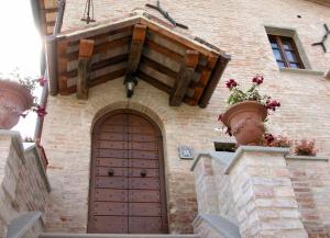 a brick building with a wooden door and flower pots at Residenza Rurale in Città di Castello