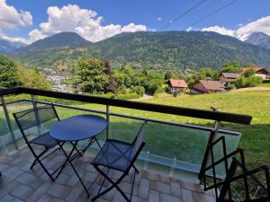 una mesa y sillas en un balcón con montañas en Charmant studio, en Saint-Gervais-les-Bains