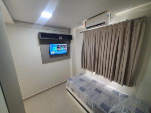Kleines Zimmer mit einem TV und einem Bett. in der Unterkunft Residencial Dinapoli in Foz do Iguaçu + 150 Fotos
