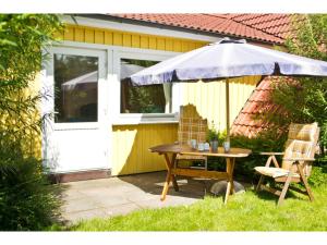 un tavolo e delle sedie sotto un ombrellone accanto a una porta di Ferienhof Ebsen a Langenhorn