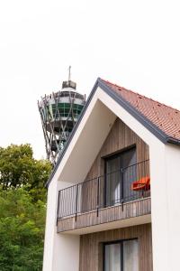 un immeuble avec un balcon et une tour de télévision en arrière-plan dans l'établissement Hiša ob stolpu, à Lendava