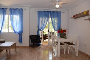 ein Wohnzimmer mit blauen Vorhängen und einem Tisch in der Unterkunft Ferienhaus für 6 Personen ca 88 m in Estrella de Mar, Murcia Costa Calida in Los Urrutias