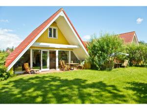 una casa gialla con tetto rosso su un prato di Ferienhof Ebsen a Langenhorn