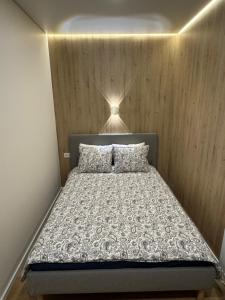 a bedroom with a bed with a wooden wall at 15 New Airport Apartment in Vilnius