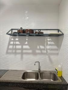 un évier de cuisine avec des casseroles sur une étagère au-dessus dans l'établissement Cozy 1-Bedroom apartment, à Ban Lum Fuang