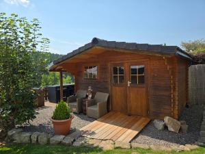 ein kleiner Holzschuppen mit einer Couch und einem Stuhl in der Unterkunft Ferienhaus Sonnenhuesli mit Sauna und Whirlpool auch Hunde sind herzlich willkommen in Lenzkirch
