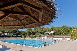 una piscina in un resort con persone sedute intorno di Hotel Club Marina Viva a Porticcio
