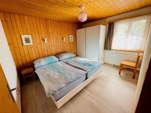 ein Schlafzimmer mit einem Bett in einem Zimmer mit Holzwänden in der Unterkunft Chalet Hofer - 5-Bettwohnung in Hasliberg Wasserwendi