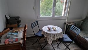 ein Tisch mit Stühlen und ein Tisch mit einem Teller mit Essen in der Unterkunft Chambre cosy avec salle-de-bain privative in Béziers