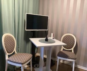 Ein Computermonitor steht auf einem Tisch mit zwei Stühlen. in der Unterkunft Appartements Haus Hashagen in Oerlinghausen