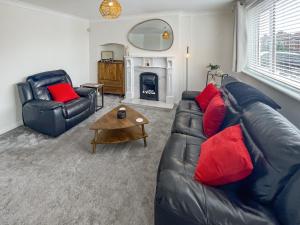 a living room with a black leather couch and red pillows at The Miners House in Deal