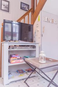 - une télévision sur un centre de divertissement blanc avec une table dans l'établissement Gîte De La Voûte, à Fécamp