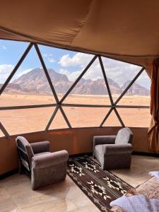 une pièce avec deux chaises et une vue sur le désert dans l'établissement Faiesal Luxury camp & Tour, à Wadi Rum