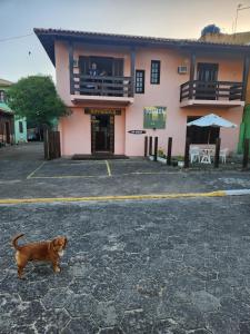a brown dog standing in front of a building at Pousada Terranova in Garopaba +1 photo