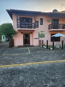 a man is looking out of the window of a pink building at Pousada Terranova in Garopaba