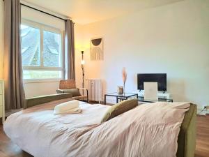 een slaapkamer met een bed, een bureau en een televisie bij Le Sweet Escape - Vue Sur La Cathédrale in Beauvais