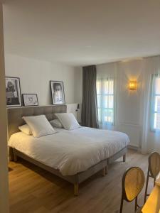 1 dormitorio con 1 cama blanca grande y 2 sillas en Maison d'Hôtes Les Sources, en Villedieu