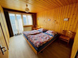 ein Schlafzimmer mit einem Bett in einer Holzwand in der Unterkunft Chalet Hofer - 5-Bettwohnung in Hasliberg Wasserwendi