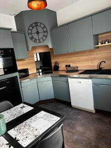 a kitchen with white cabinets and a clock on the wall at 2-room apartment near Marais and CV in Bourges