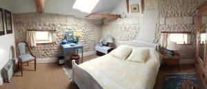 une chambre avec un lit et un mur en pierre dans l'établissement Chariaud, near Aubeterre sur Dronne, à Saint-Romain