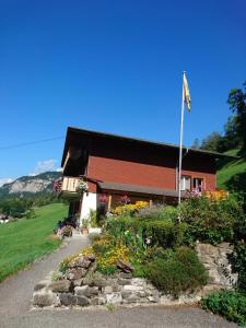 un edificio con una bandera y flores delante de él en Obererli, en Hasliberg