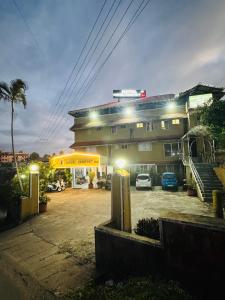 a building with cars parked in a parking lot at night at Hotel caveri comfort in Madikeri