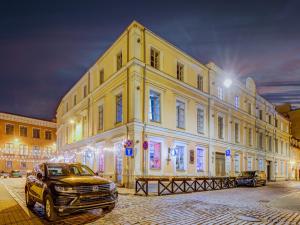 un grand bâtiment jaune avec une voiture garée devant lui dans l'établissement Authentic Old Riga Heritage, 2BR, Grand Ceilings, à Tīnūži