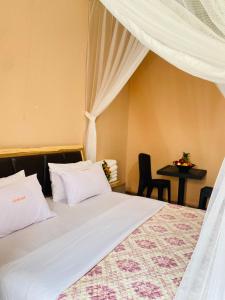 a bedroom with a bed with white sheets and a table at Jseason Faith-based retreat resort in Kagolomolo