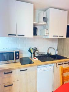 une cuisine avec des armoires blanches et un micro-ondes dans l'établissement Osciere Ski in - Out, à Val Thorens