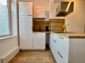 Una cocina con gabinetes blancos y encimera. en Cocon Saint-Arnould, en Saint-Omer