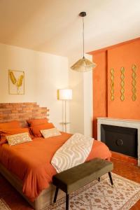 a bedroom with an orange bed and a fireplace at Cosy Cloître, apt authentique centre Arles in Arles