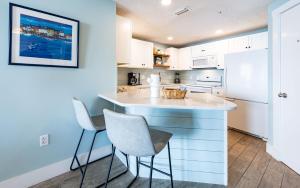 - une cuisine avec un comptoir blanc et 2 chaises dans l'établissement Phoenix X 711 condo, à Orange Beach