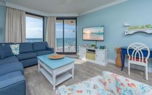 un salon avec un canapé bleu et une télévision dans l'établissement Phoenix X 711 condo, à Orange Beach