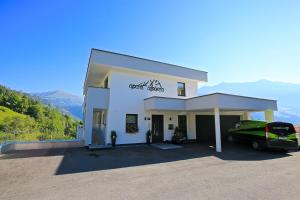 Un bâtiment blanc avec une voiture garée devant. dans l'établissement Apart Alpinea, à Ladis