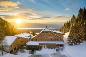 un chalet dans la neige avec le soleil en arrière-plan dans l'établissement La Mainaz Hôtel Restaurant Genève - Gex - Mijoux, à Gex