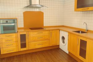 una cucina con armadi in legno, lavatrice e asciugatrice di Apartamentos El Paso a Pedrera Altre 2 foto