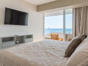 una camera da letto con un letto con una televisione e la spiaggia di De lujo Con vista al mar en el Malecon a Mazatlán
