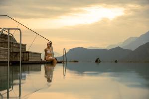 拉伊韦斯理想公园酒店的坐在游泳池边的比基尼的女人