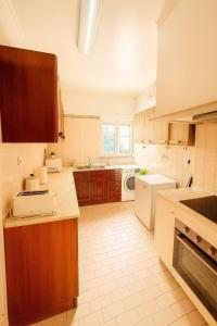 cocina grande con armarios de madera y electrodomésticos blancos en Cascais Ocean Apartment, en Cascais