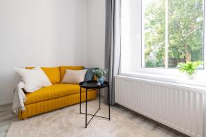 ein gelbes Sofa in einem Zimmer mit einem Fenster in der Unterkunft Nowoczesne Studio Mała Andrzeja, Kawalerka Inowrocław, Modern Studio, kamienica in Inowrocław