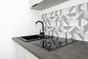 eine Küche mit einer Spüle und einer Fliesenwand in der Unterkunft Nowoczesne Studio Mała Andrzeja, Kawalerka Inowrocław, Modern Studio, kamienica in Inowrocław