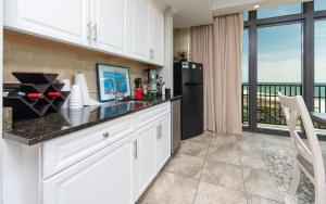 a kitchen with white cabinets and a black refrigerator at The Oasis 411 formerly Phoenix West II 411 in Orange Beach