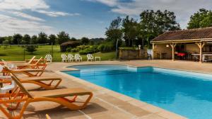 a swimming pool with chairs and a house at Gîte Charly in Salignac Eyvigues +14 photos