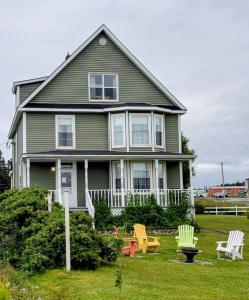 a house with two lawn chairs in front of it at Applewood Inn Bed and Breakfast in Twillingate