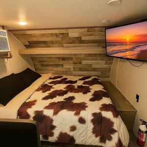 a bedroom with a bed and a flat screen tv at Cozy RV Farm Stay with Hot Tub WiFi and Coffee 5 Min to AHCL Hospital and Redbud Park in Clearlake